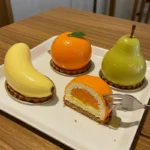 Fruit Shaped Pastries 8 Pear, orange, and banana-shaped pastries on a white plate