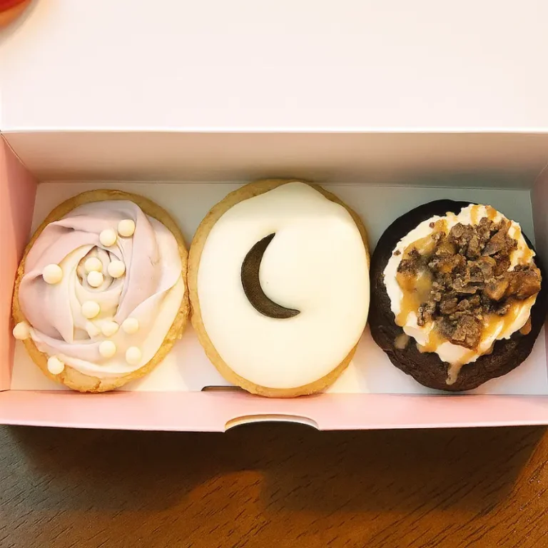 Kardashian Crumbl Cookies: Viral Flavors You Must Try Now 7 kardashian crumbl cookies in a pink box with swirled frosting and toppings