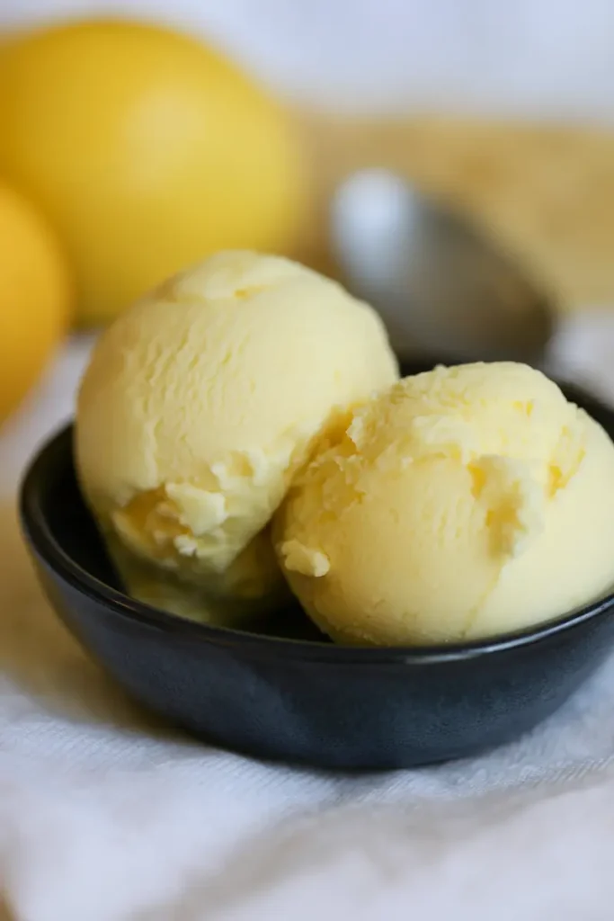 Meyer Lemon Ice Cream Magic: Rich, Lush & Dairy-Free 12 Eggless meyer lemon ice cream with a creamy scoop next to whole lemons
