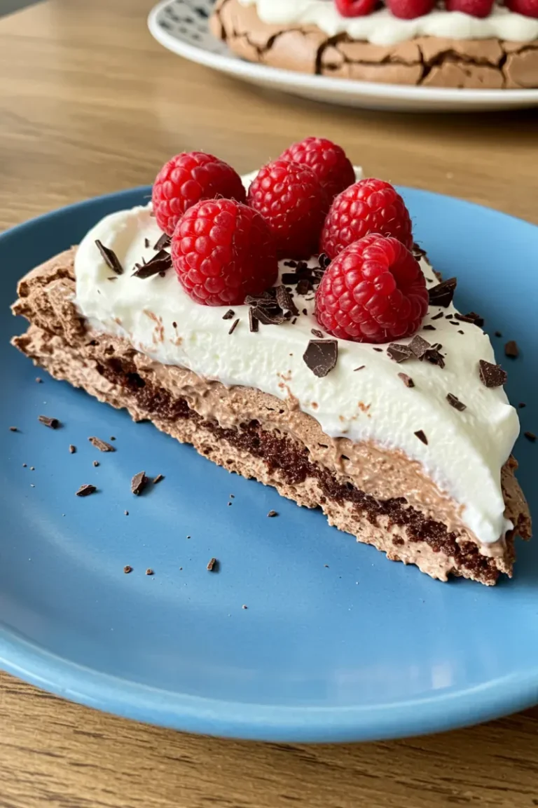 Nigella Chocolate Pavlova: Make Easy Sweet Recipe 13 Slice of nigella chocolate pavlova topped with whipped cream, raspberries, and chocolate curls