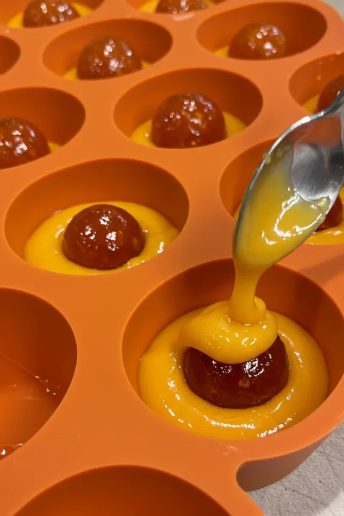 Orange Shaped Pastry 20 hands smoothing mousse over filled pastry molds