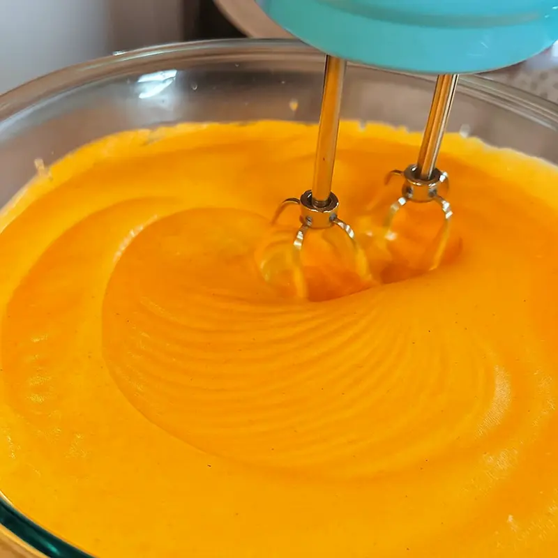 How To Make Orange Shaped Ice Cream 12 Light orange ice cream base being mixed with a hand mixer in a bowl