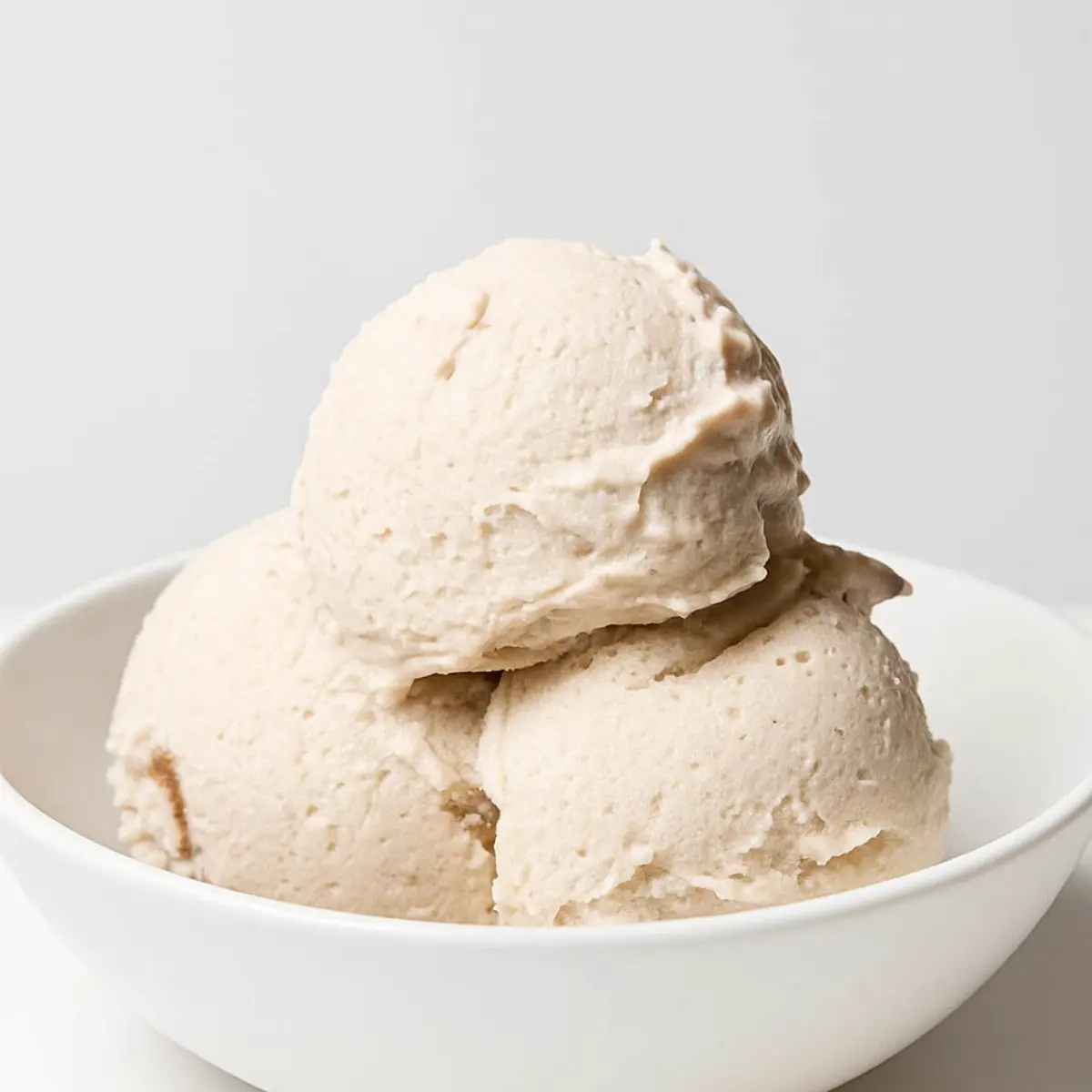 Best Protein Ice Cream Ninja Creami Recipes 2 A pint of vanilla ice cream with a vibrant strawberry swirl from a dairy free ninja creami recipe.