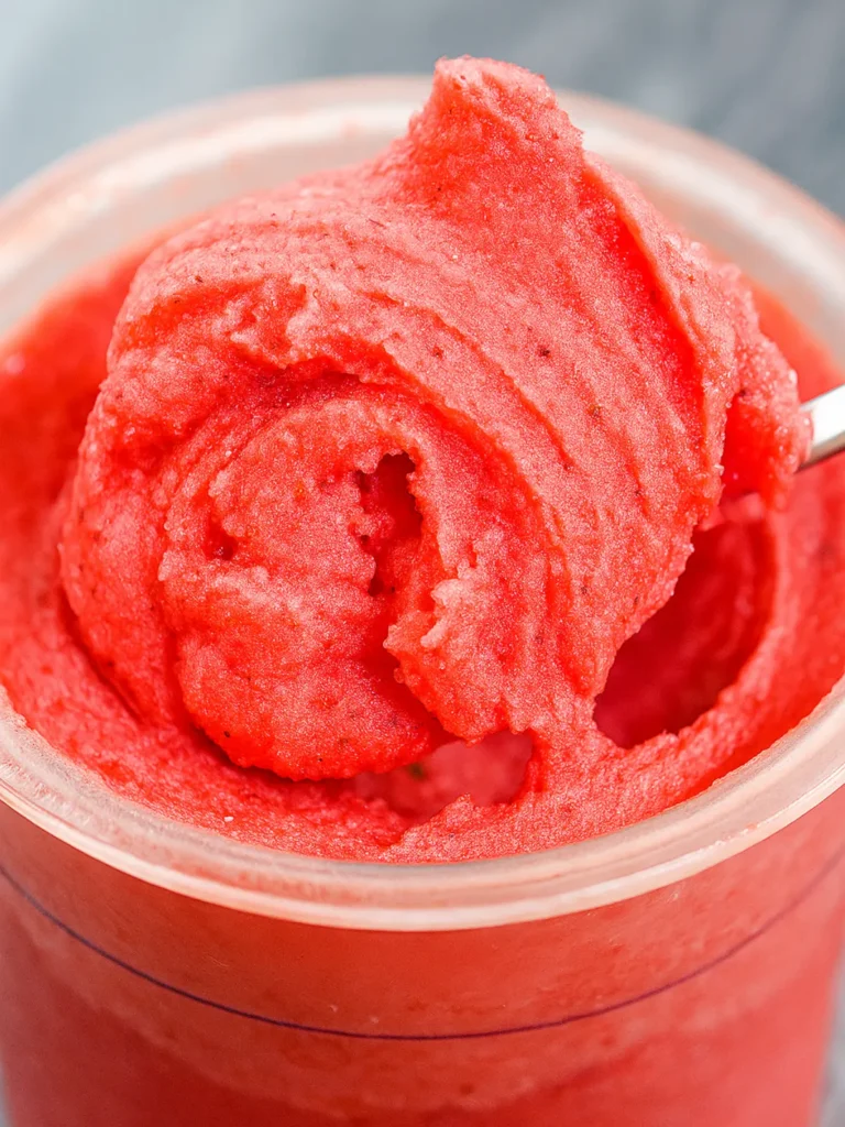 A bright pink scoop of strawberry sorbet, a popular fruit-based option for keto ninja creami recipes.